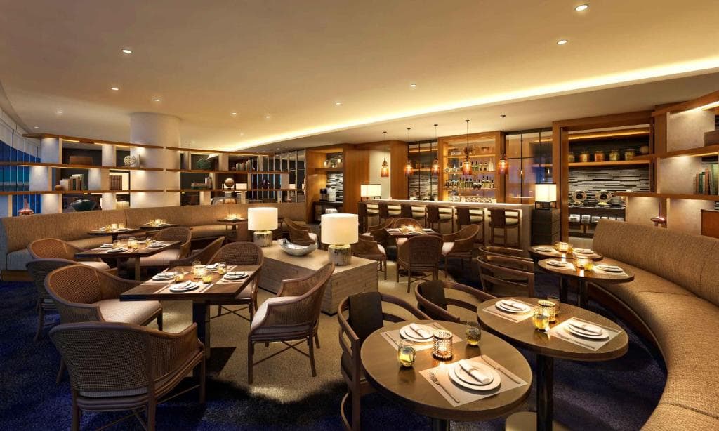 ザツバキタワーのリナラクラブラウンジ温かみのある照明と茶色の椅子やテーブル、ソファー間接照明が置かれている