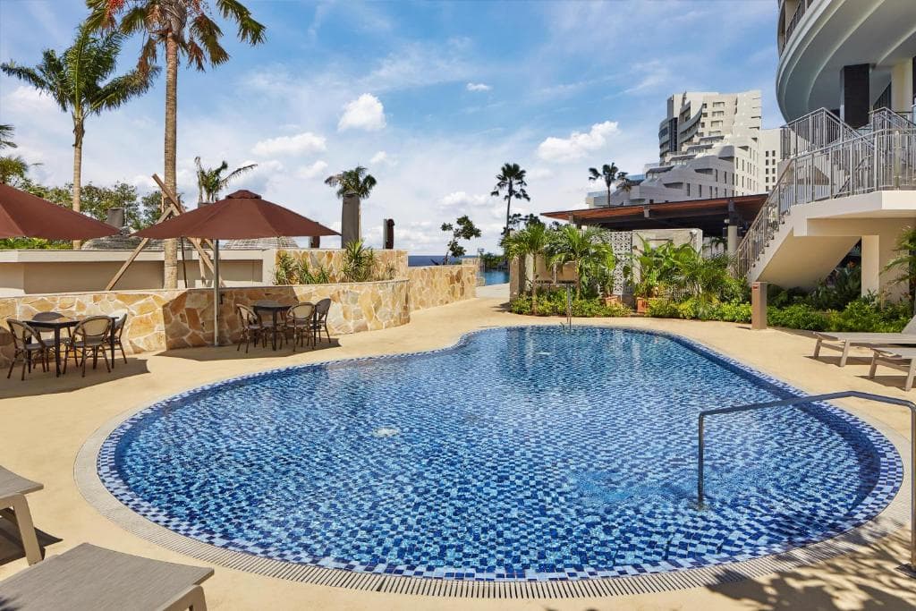 ザ ツバキタワーのキッズプール 青と水色のタイルでできた楕円形のプール。周りには椅子やテーブルもある