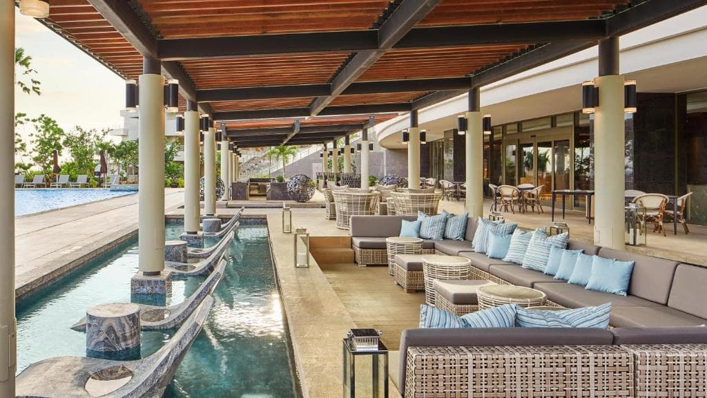 ザ ツバキタワーのプールサイドバー 水色のクッションがたくさんレイアウトされた南国風のソファーや1人がけのリクライニングチェア