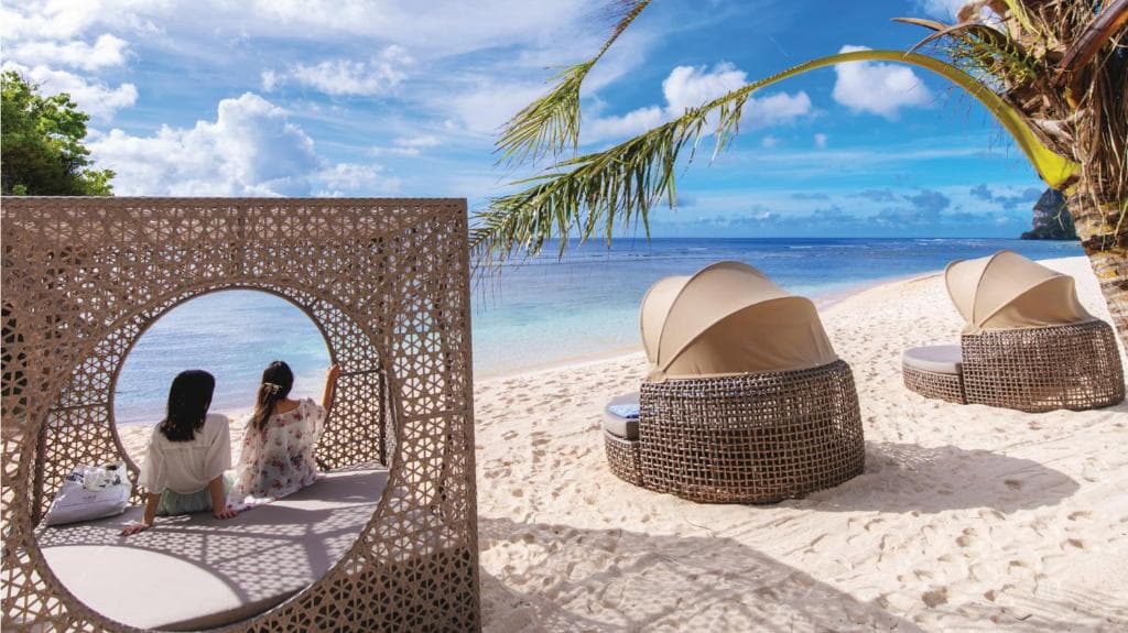 ホテルニッコーグアム横のガンビーチ 専用ガバナでくつろぐ2人の女性 砂浜と青い海。青い空