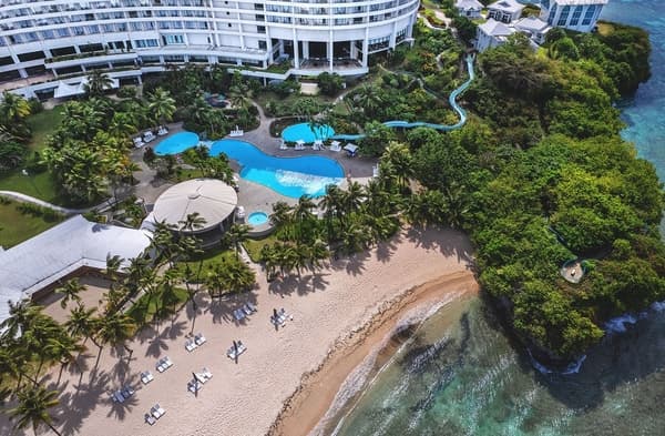 ホテルニッコーグアムのスライダーとプール 緑の木々や砂浜、海と繋がっている